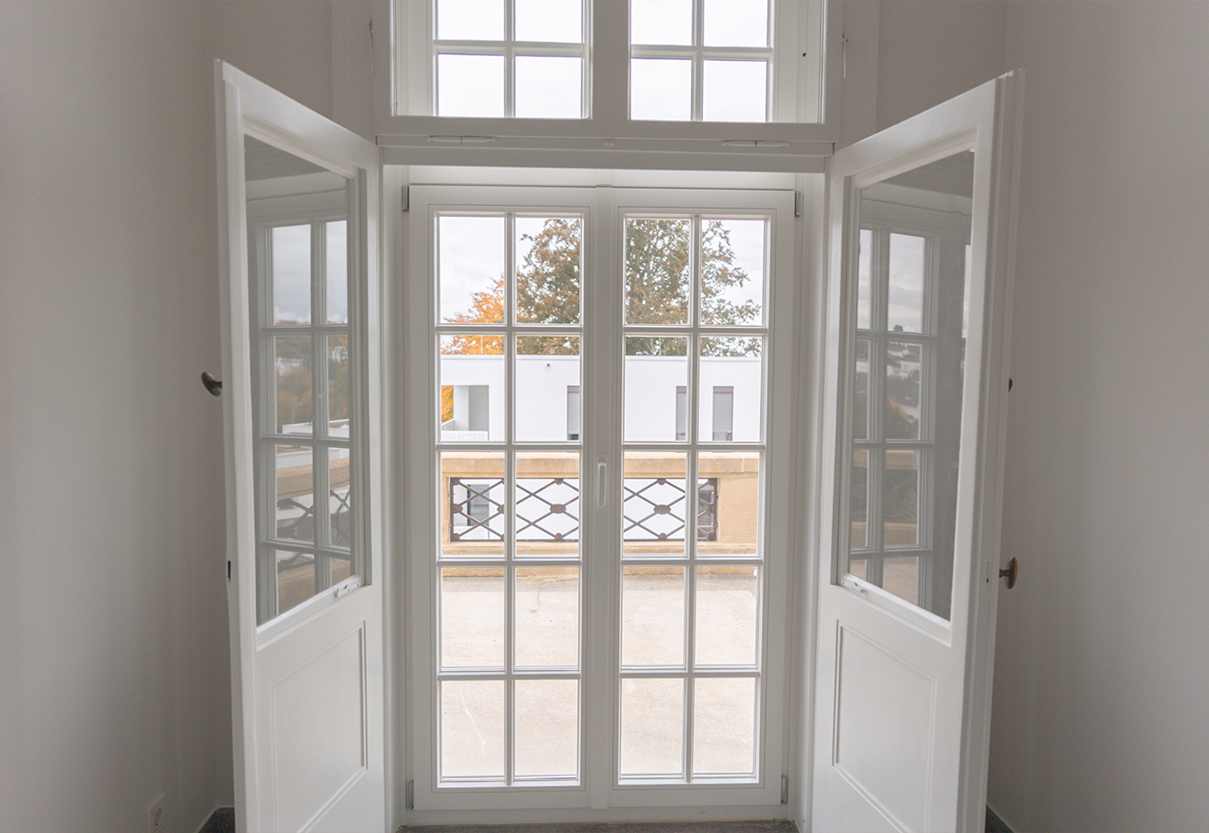 Geöffnete Türen mit Blick in einen Raum mit Pflanzen und Matte. Geöffnete Türen mit Blick in einen Raum mit Pflanzen und Matte.