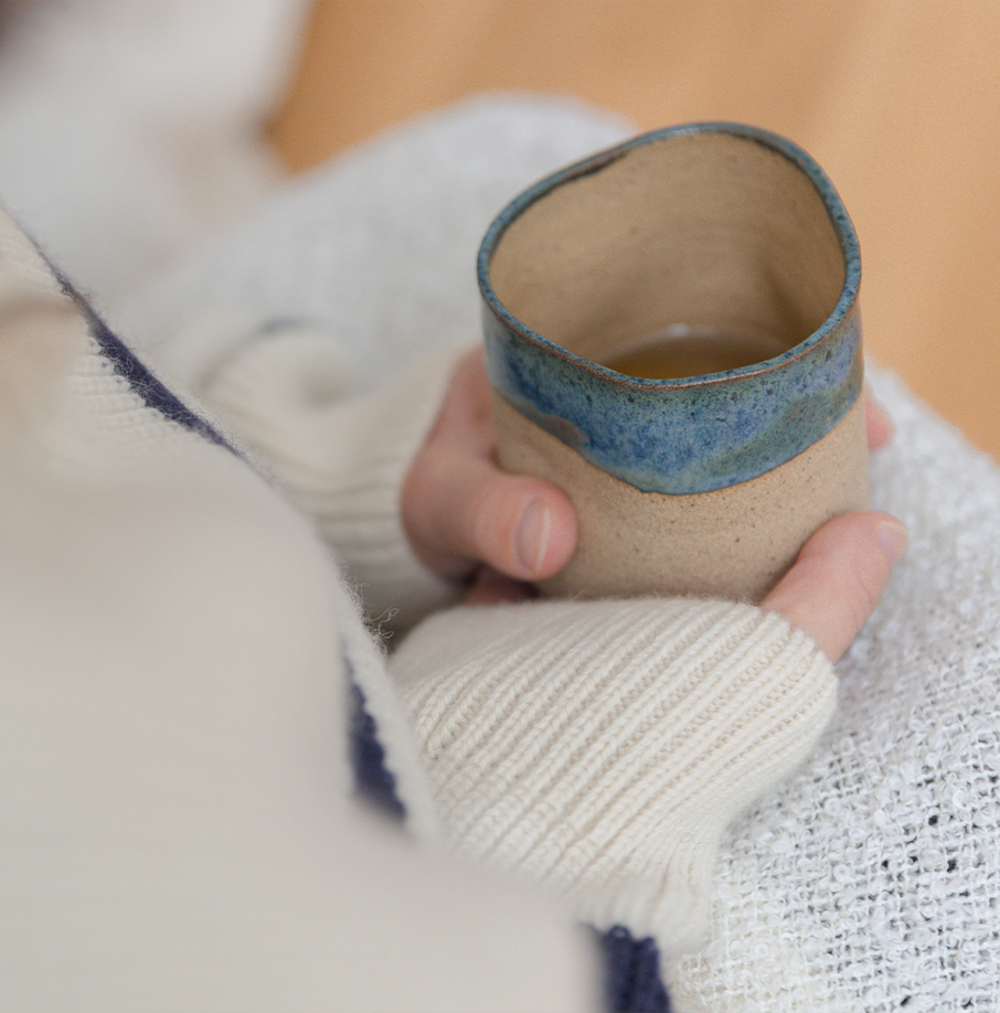Hände halten eine Tasse in einer Decke. Hände halten eine Tasse in einer Decke.