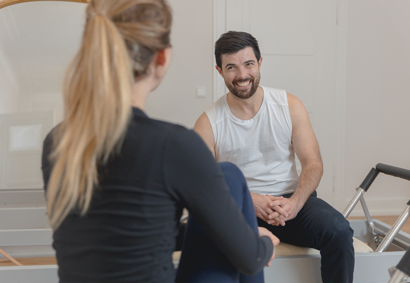 Zwei Personen sitzen und unterhalten sich auf einem Pilates Reformer. Zwei Personen sitzen und unterhalten sich auf einem Pilates Reformer.
