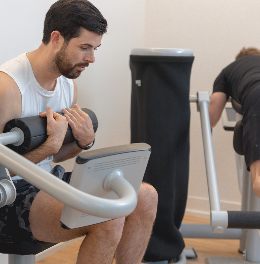 Person trainiert an einem Kraftgerät. Person trainiert an einem Kraftgerät.