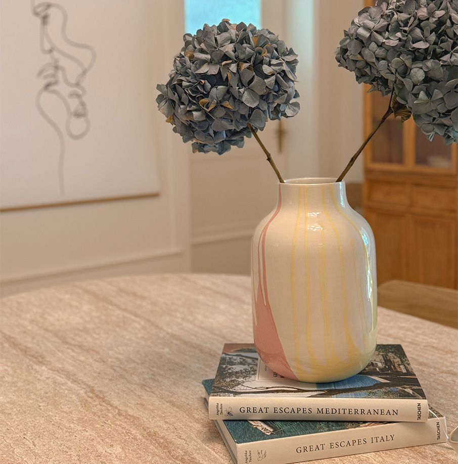 Vase mit zwei dekorativen Zweigen auf einem Tisch. Vase mit zwei dekorativen Zweigen auf einem Tisch.